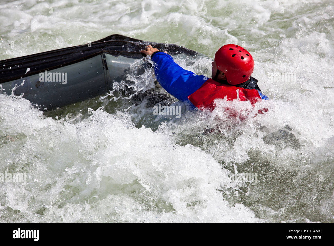 Canoa in acqua bianca in rapide sul fiume con la canoeist cadere al di fuori della sua barca Foto Stock