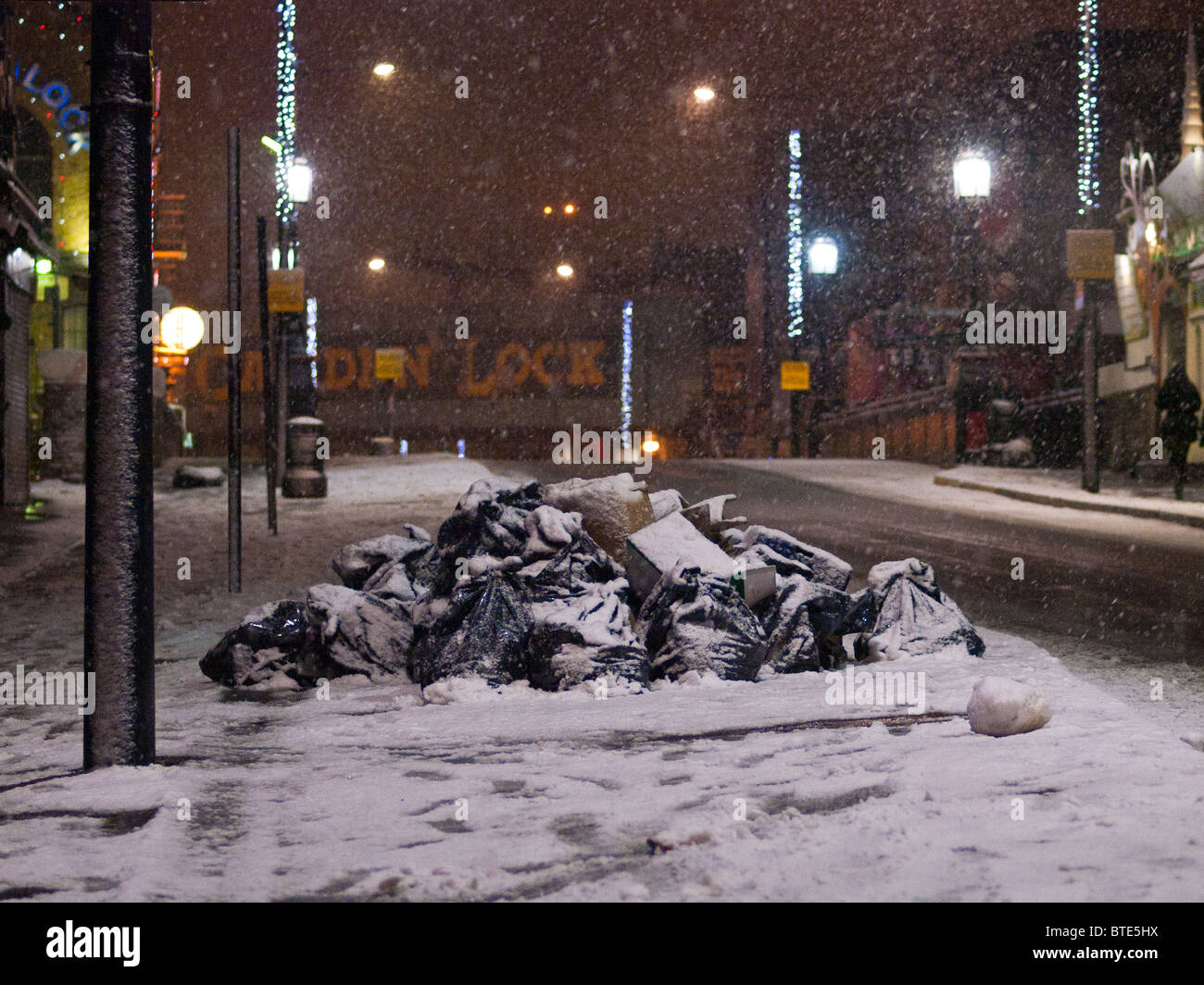 Rifiuti su una strada innevata di notte in Camden Town, Londra, Inghilterra, Regno Unito Foto Stock