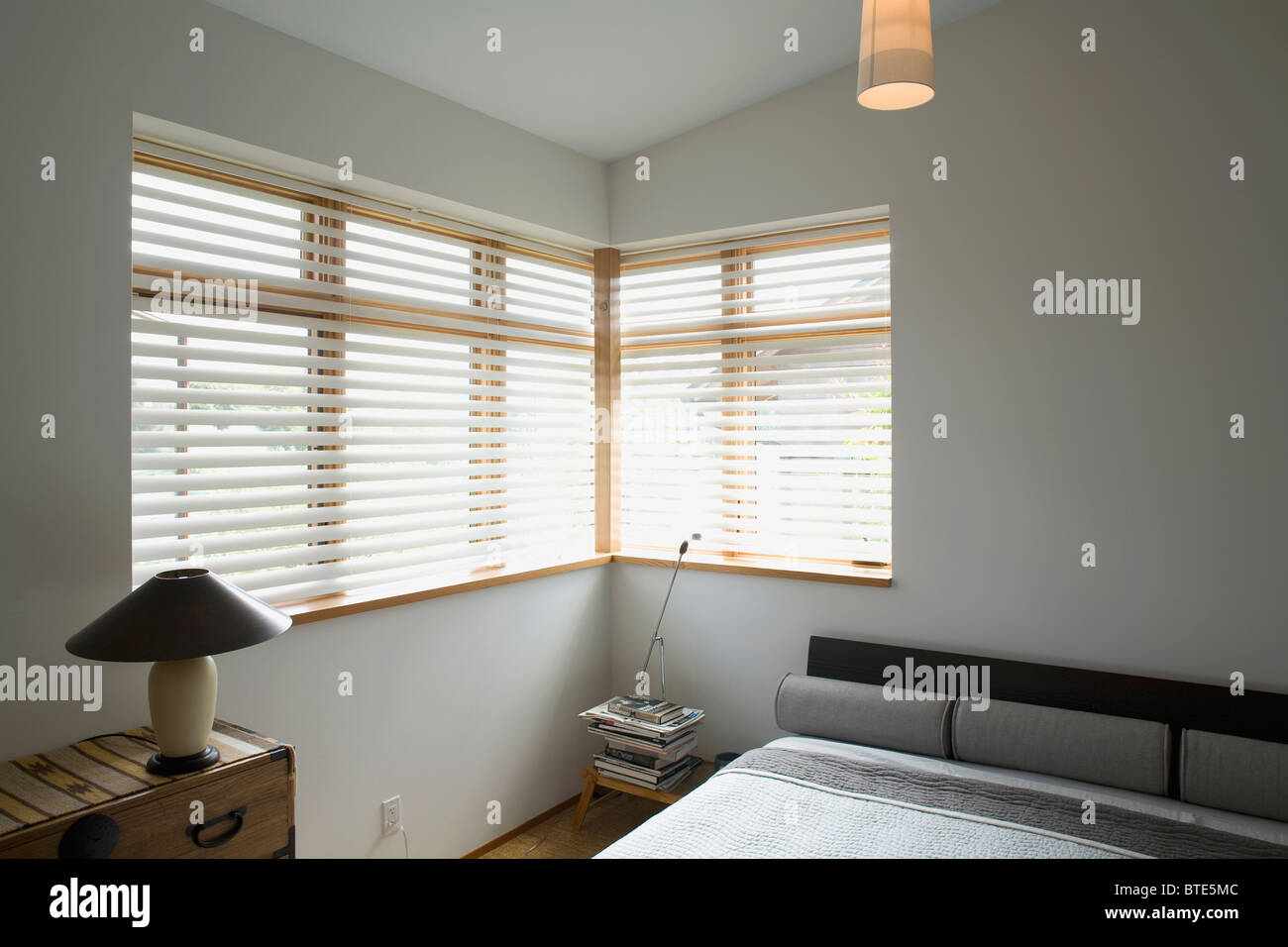 Contemporanee camere da letto con letto grigio e finestre ad angolo Foto Stock