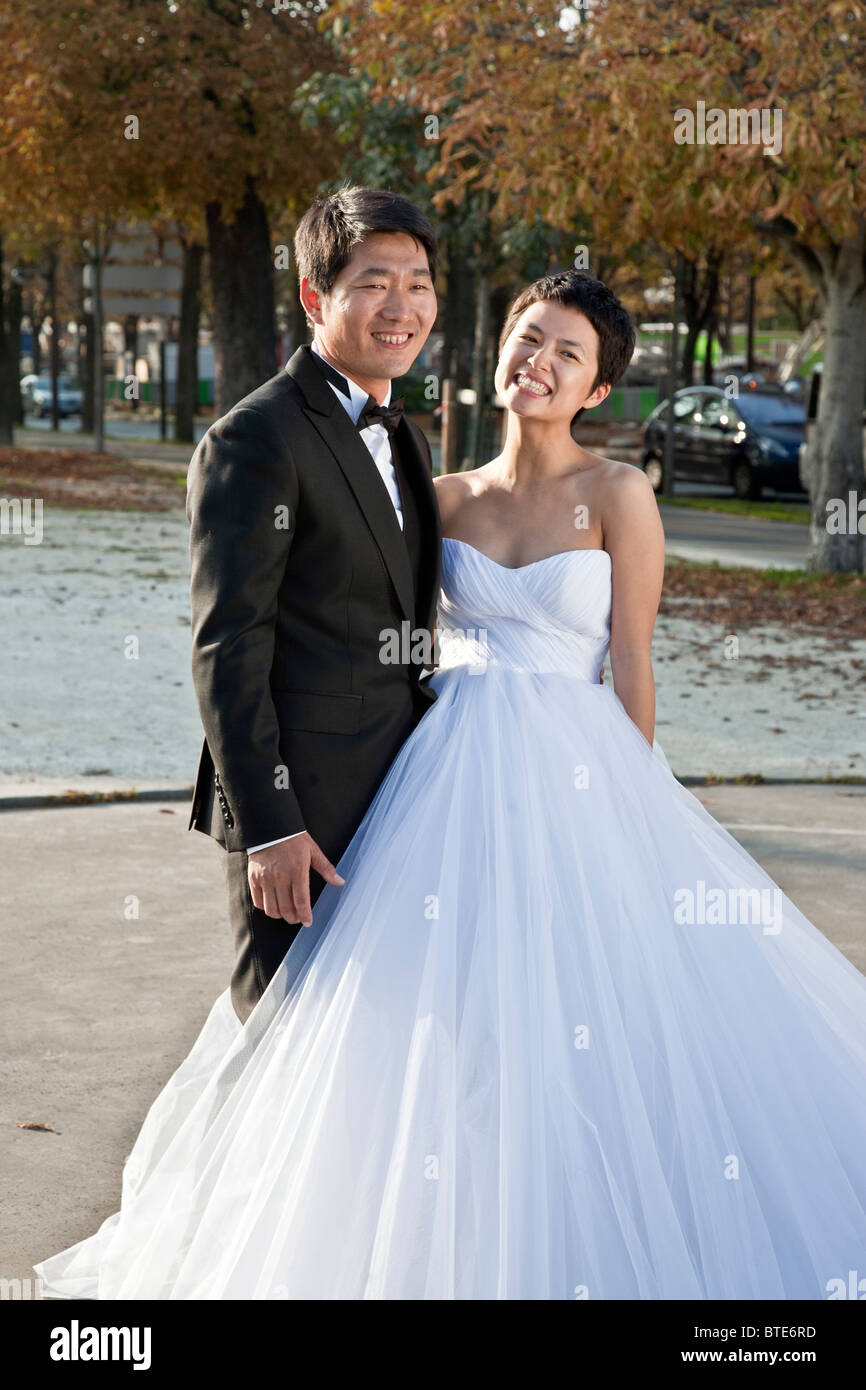 Radiant bride asiatico & groom pongono per matrimonio ritratto sul lungomare di Cours de la Reine in una calda giornata d'autunno a Parigi Foto Stock