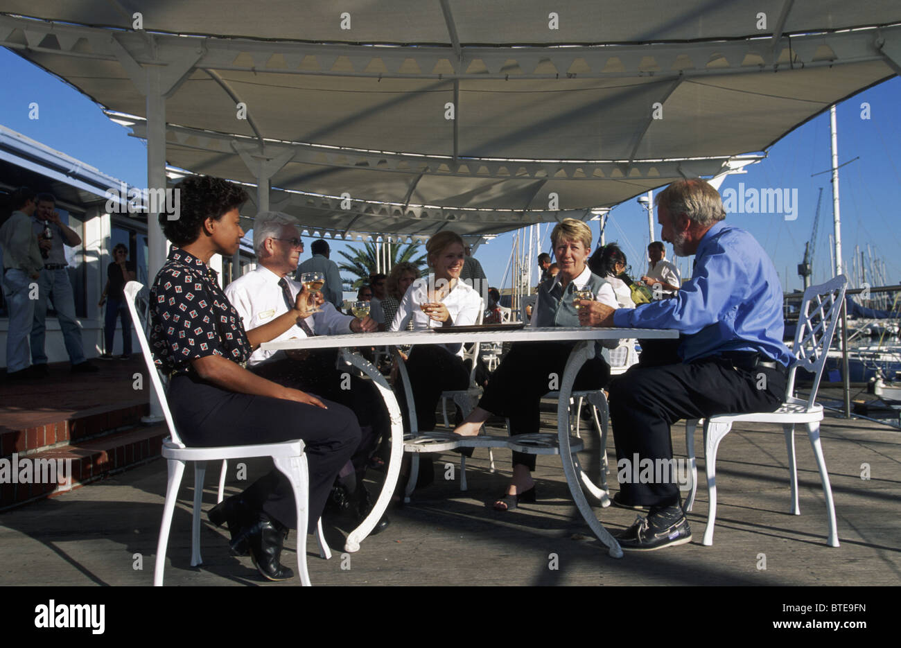 Un gruppo di ben vestito gli ospiti possono godere di un bicchiere di vino sul terrazzo al Cape Royal Yacht Club di Cape Town Foto Stock