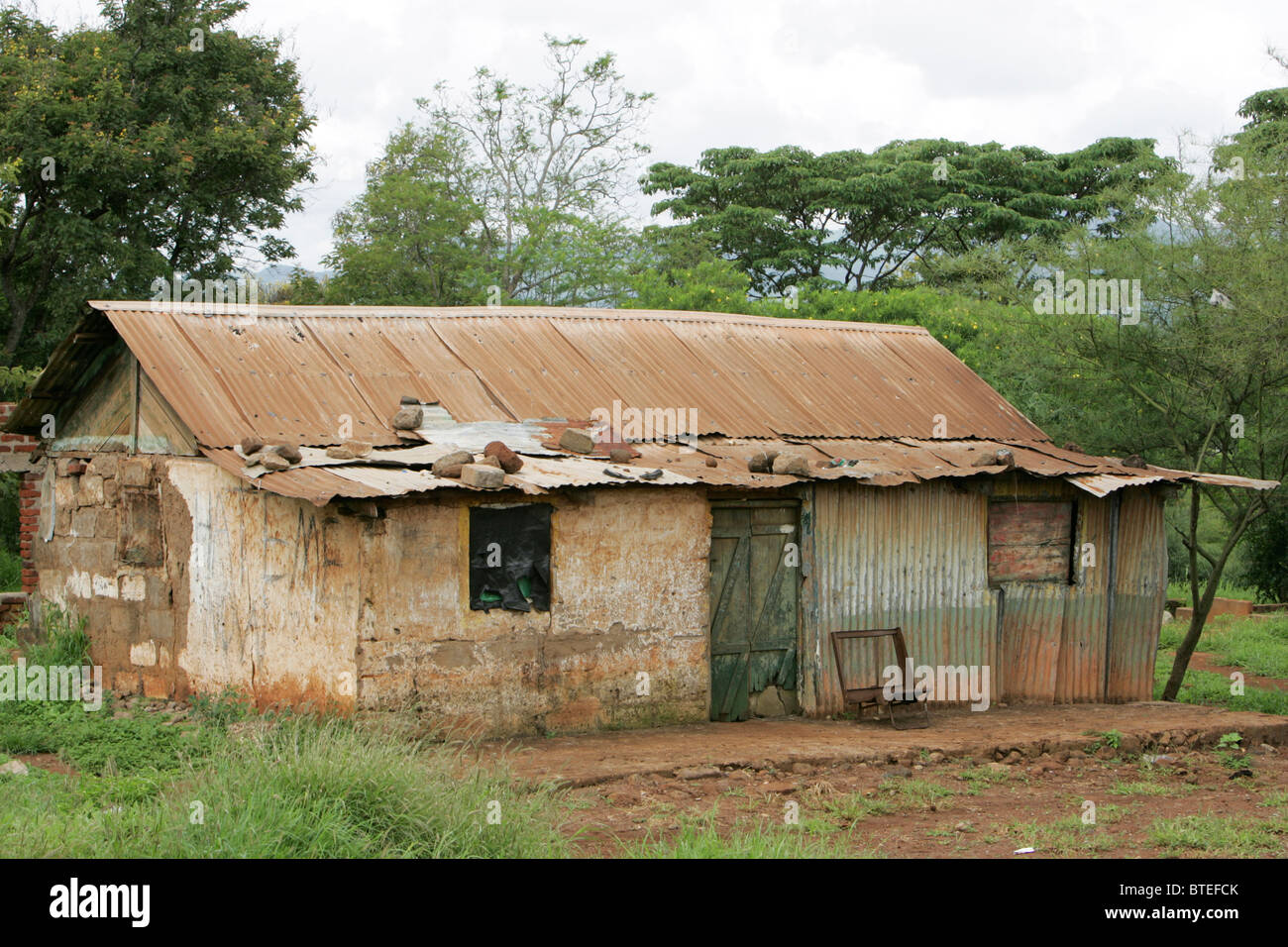 Abbandonato il vecchio ferro corrugato e fango-casa di mattoni Foto Stock