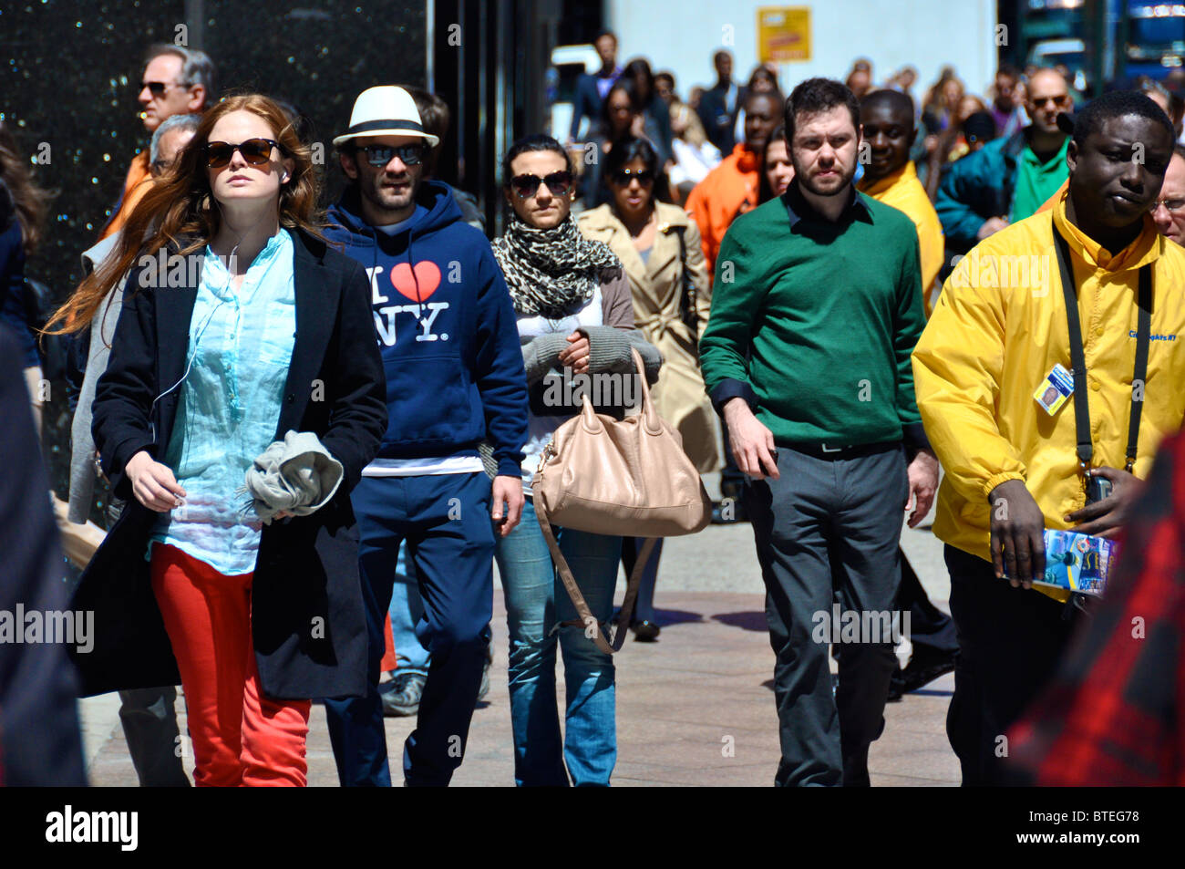 Si affollano nella città di New York, camminano per la strada in una giornata di sole. Foto Stock