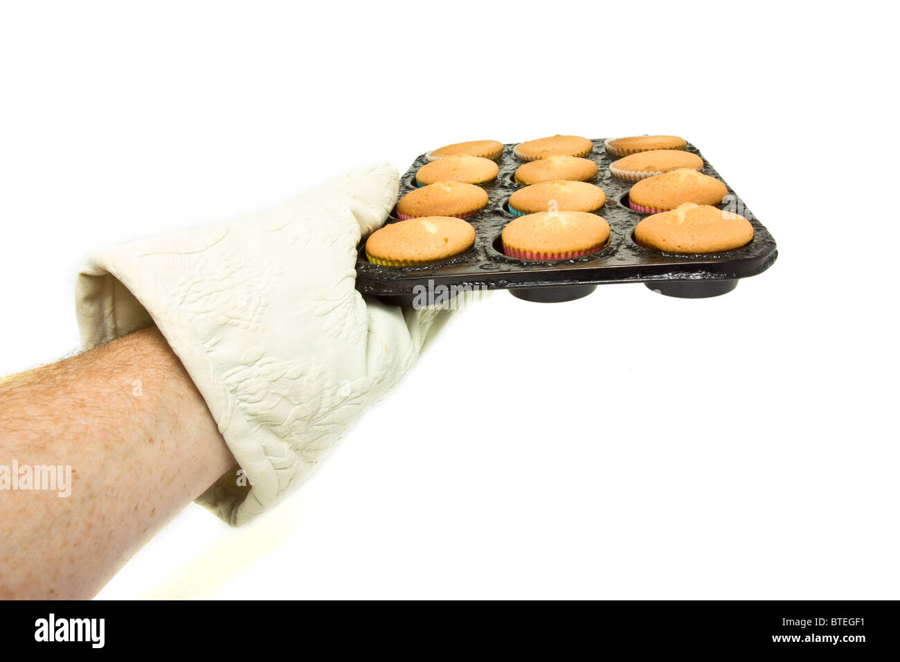 Mano indossando forno mit tenendo il vassoio a caldo di cucinate fresche e torte di coppa. Foto Stock