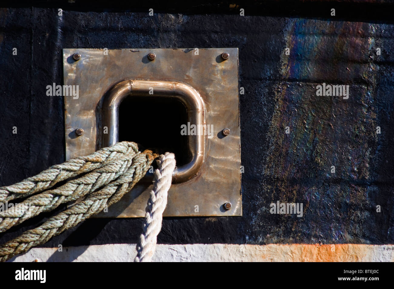 Barca dettaglio mostrante le funi a treccia in uscita di una piazza foro di metallo sul lato della barca Foto Stock
