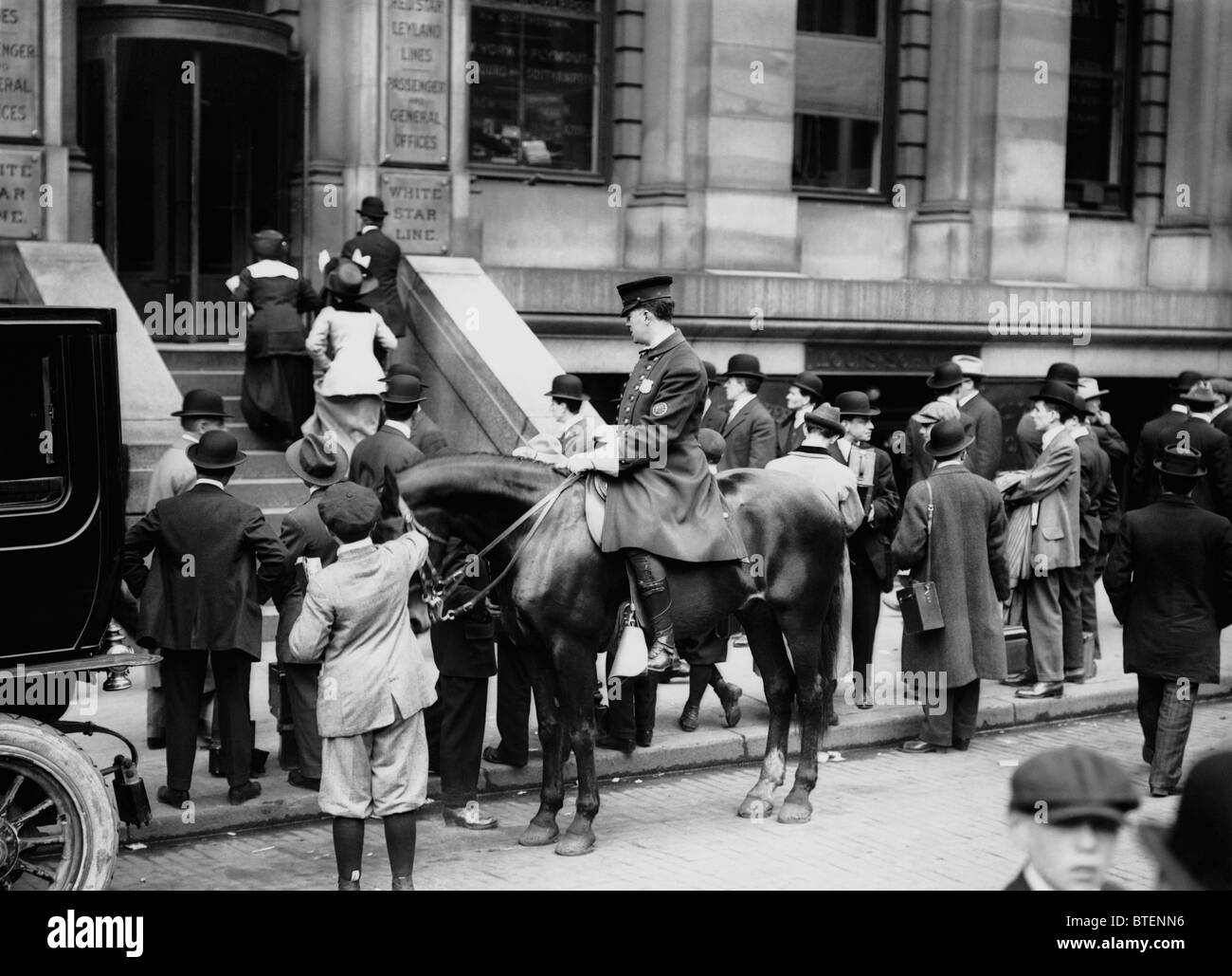 Un poliziotto di pattuglie al di fuori della White Star Line uffici a New York come la folla raccolta dopo il disastro del Titanic nel 1912. Foto Stock