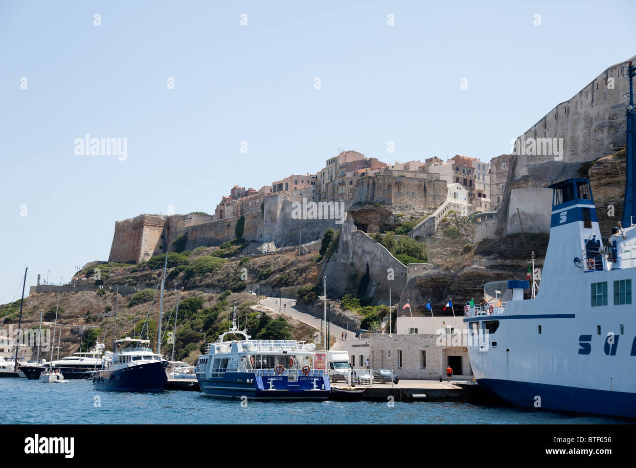 Il traghetto e la barca turistica docking dalla cittadella nel porto di Bonifacio. Foto Stock