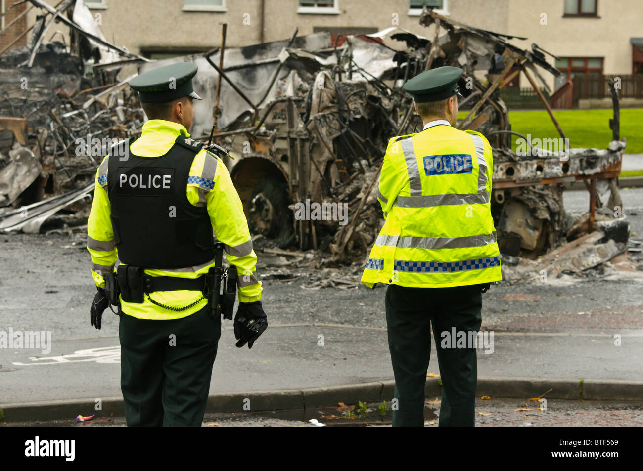 Due ufficiali della polizia sulla scena di disordini civili, dove un autobus è stato dirottato e bruciato. Foto Stock