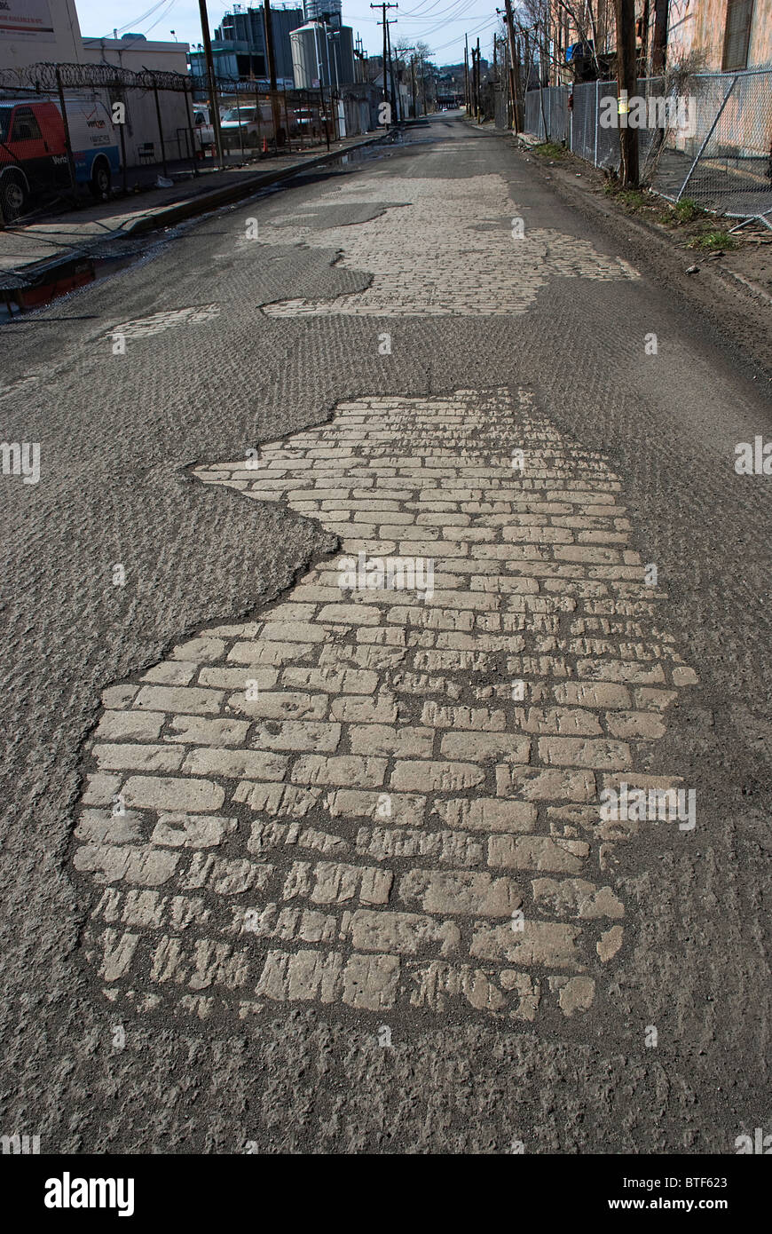 Esposto in pietra vecchia strada di fondazione sotto forma di macadam sgrossato attende resurfacing Foto Stock
