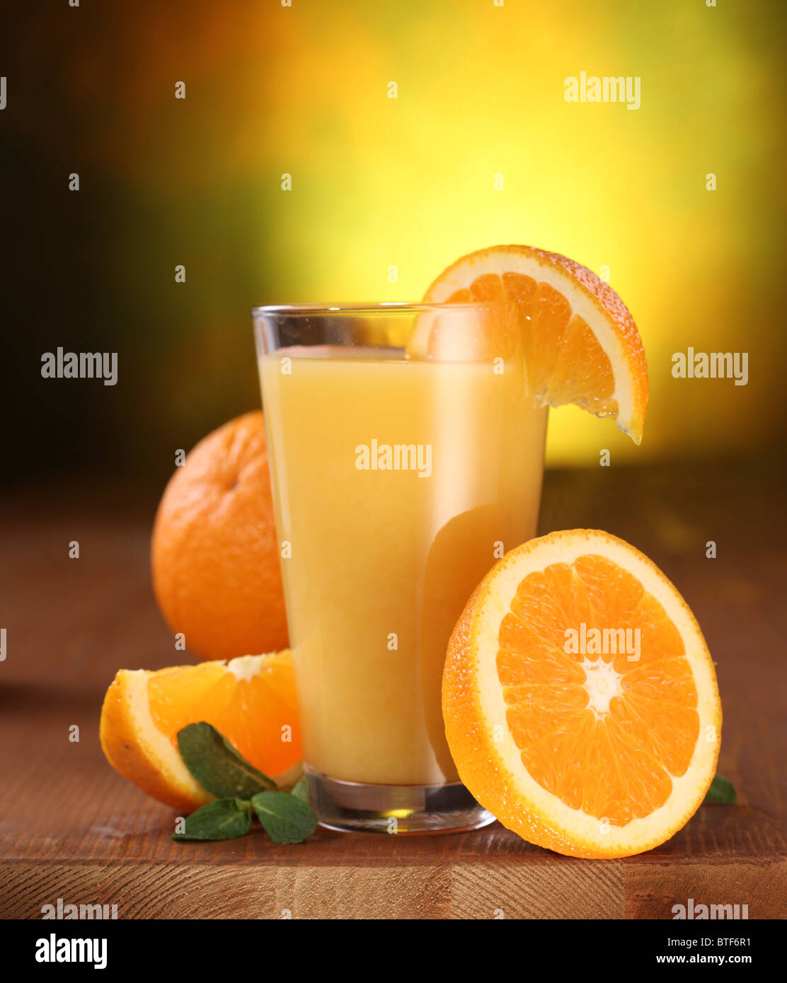 Still Life: arance e bicchiere di succo di frutta su un tavolo di legno. Foto Stock