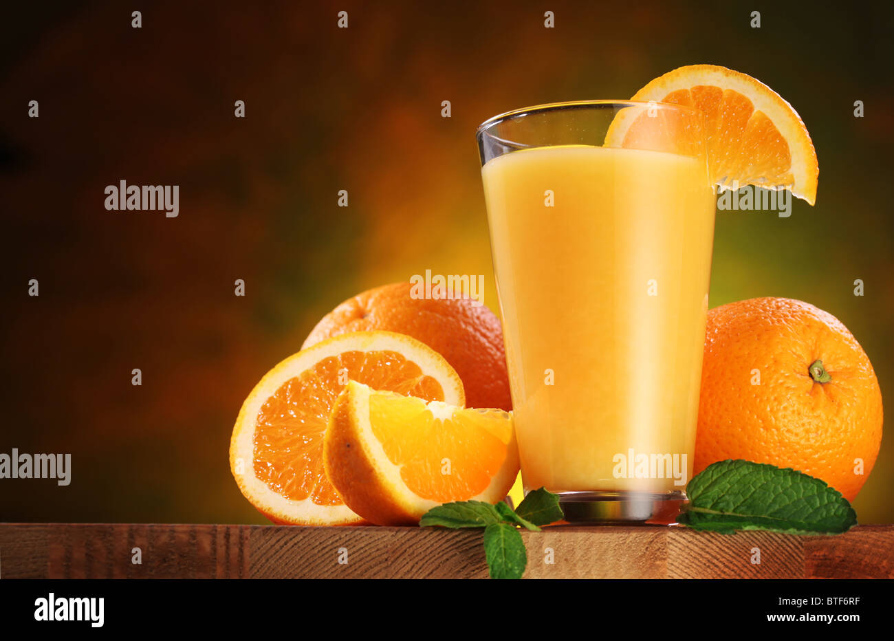 Still Life: arance e bicchiere di succo di frutta su un tavolo di legno. Foto Stock
