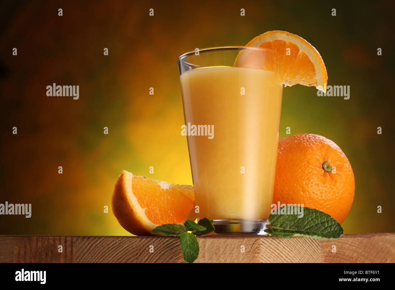Still Life: arance e bicchiere di succo di frutta su un tavolo di legno. Foto Stock