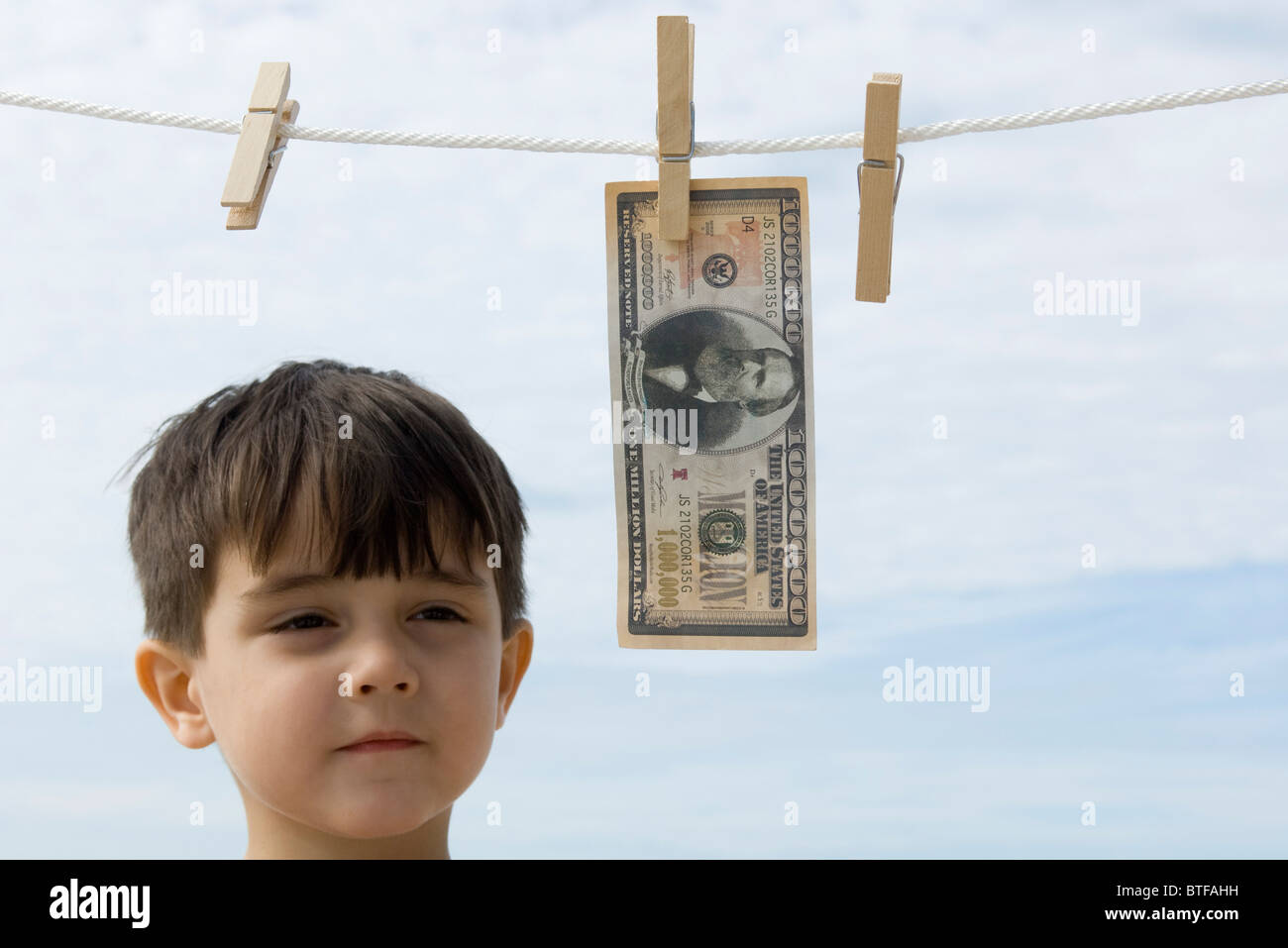 Ragazzo contemplando un milione di dollaro appeso su vestiti-line Foto Stock