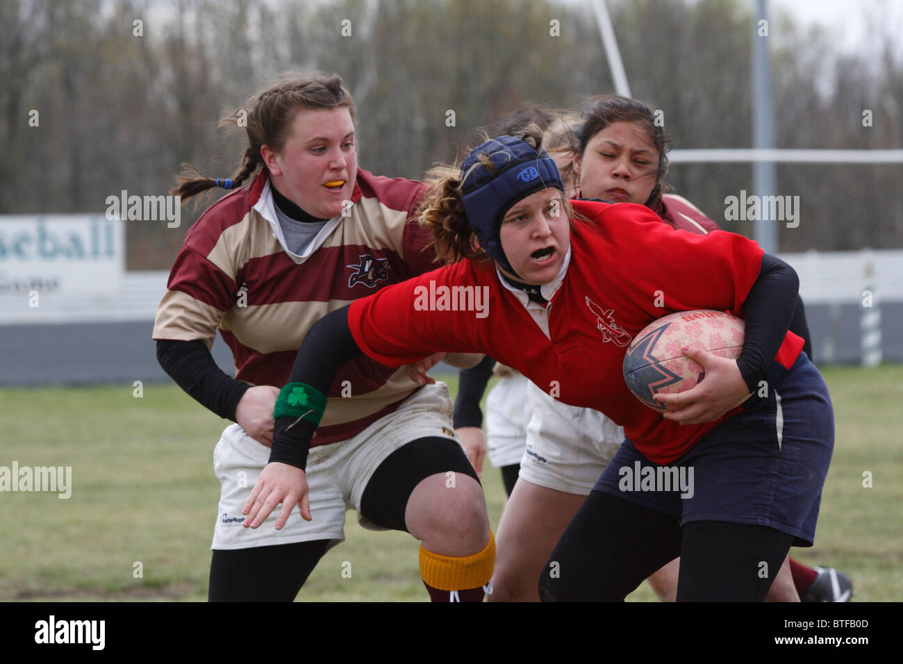 Una università americana il giocatore porta la palla contro Norwich University durante una donna partita di rugby. Foto Stock