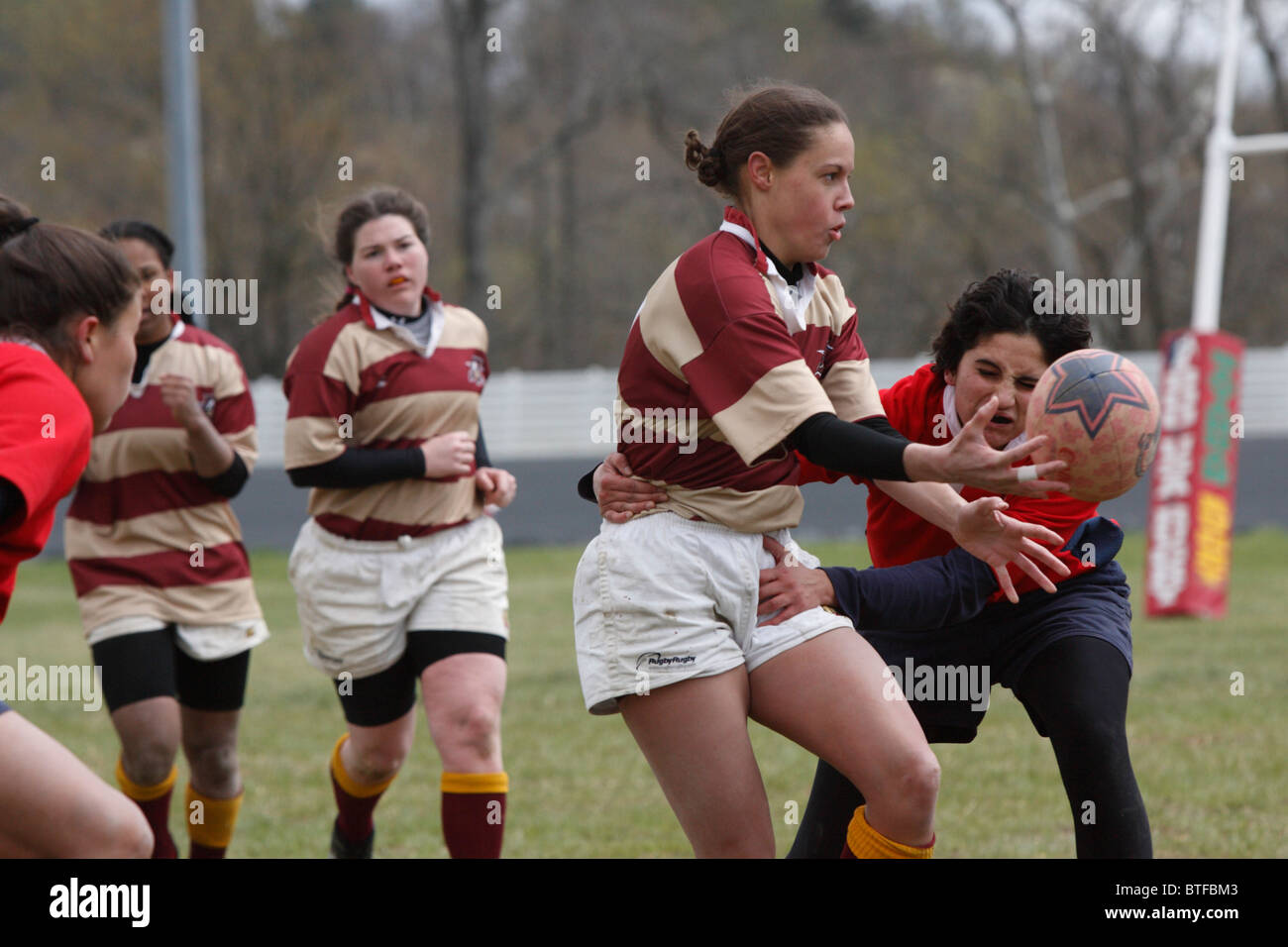 Una università di Norwich il giocatore passa la palla contro Università americana durante una donna partita di rugby. Foto Stock