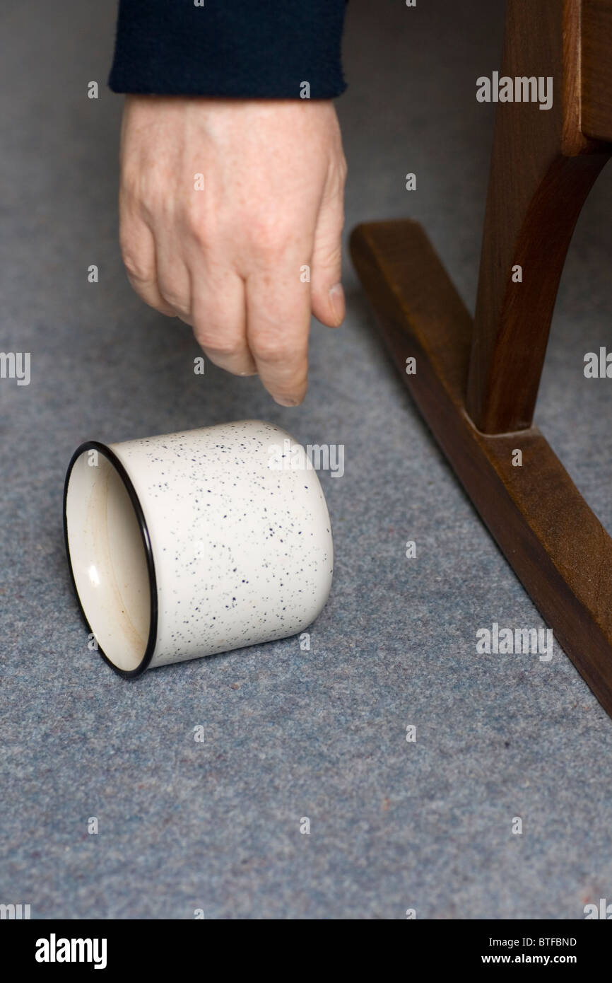 Una tazza si trova accanto alla mano che caduto. Foto Stock