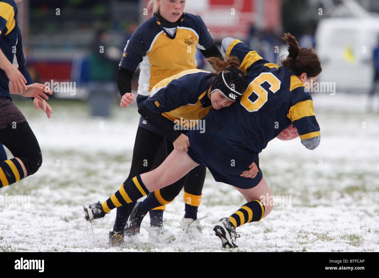 Un George Washington University player è affrontato da un'Accademia Navale avversario durante un snowy donna partita di rugby. Foto Stock