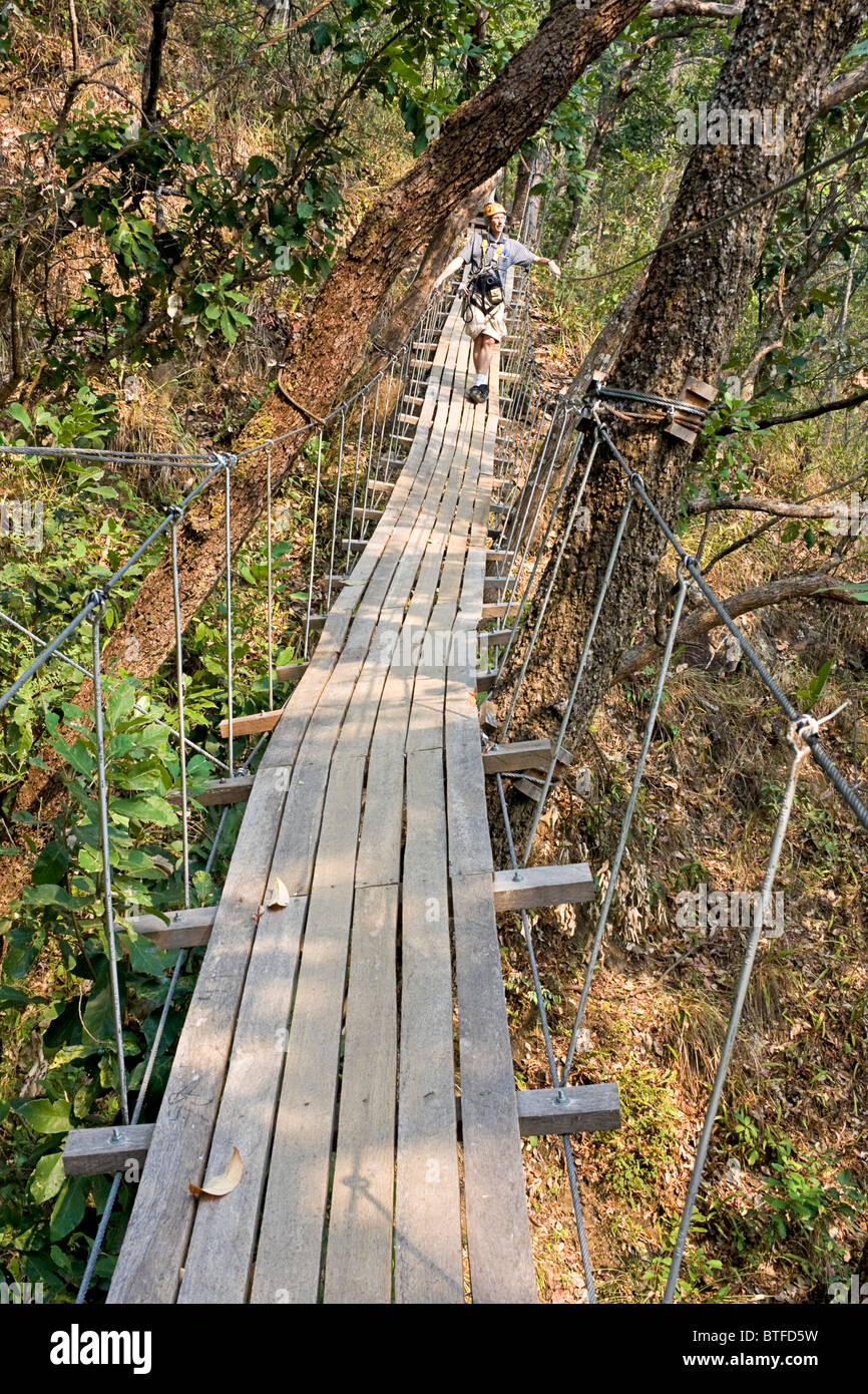 Uomo attraversa uno dei ponti di sky ad una zipline avventura in Chiang Mai area della Thailandia. Foto Stock