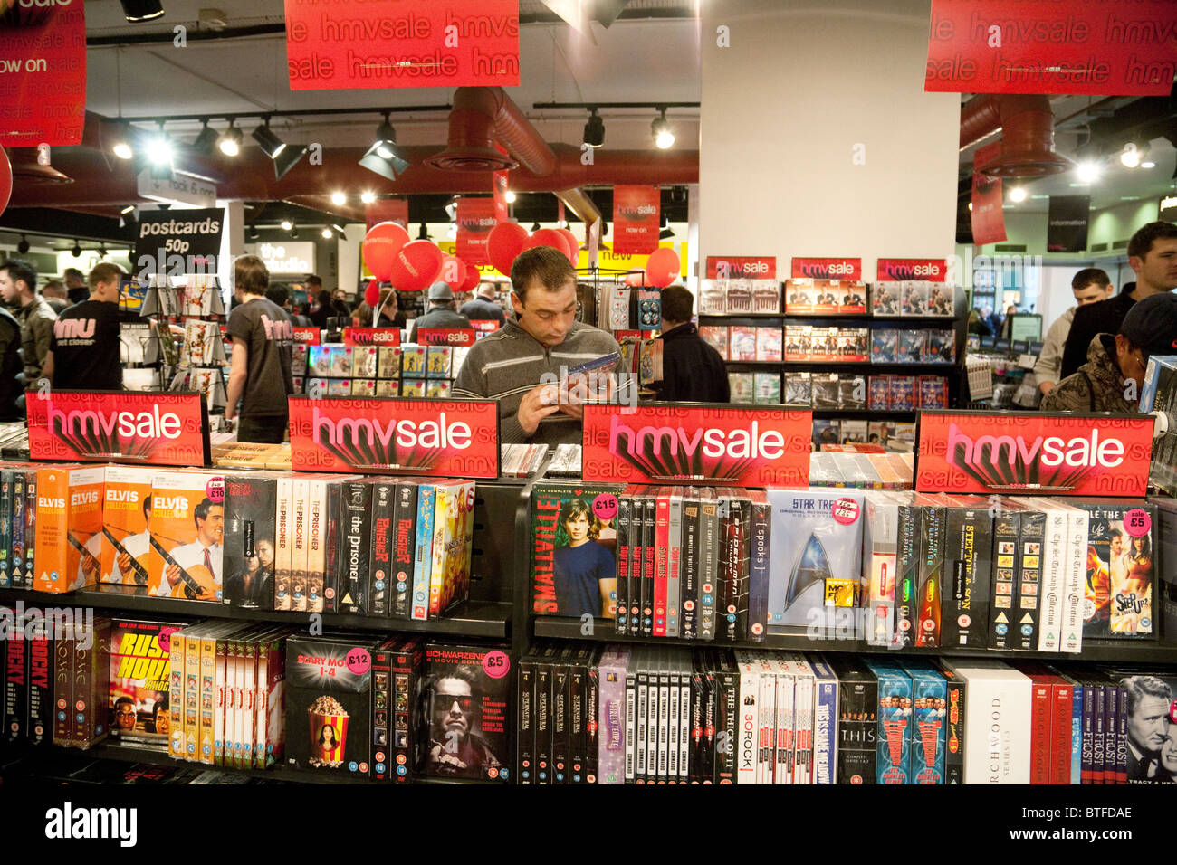 Un uomo che guarda il DVD DVD in vendita HMV, interno, HMV store, filiale di Cambridge, Regno Unito Foto Stock