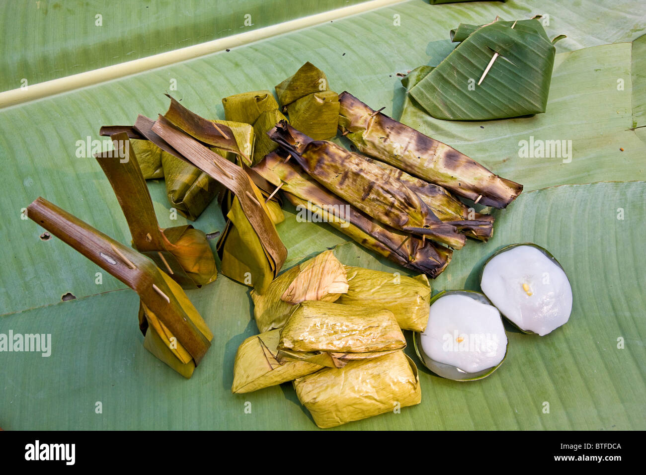 Riso locale e noce di cocco in base cibi avvolti in foglie e servita su foglie di banano. Nel nord della Thailandia. Foto Stock