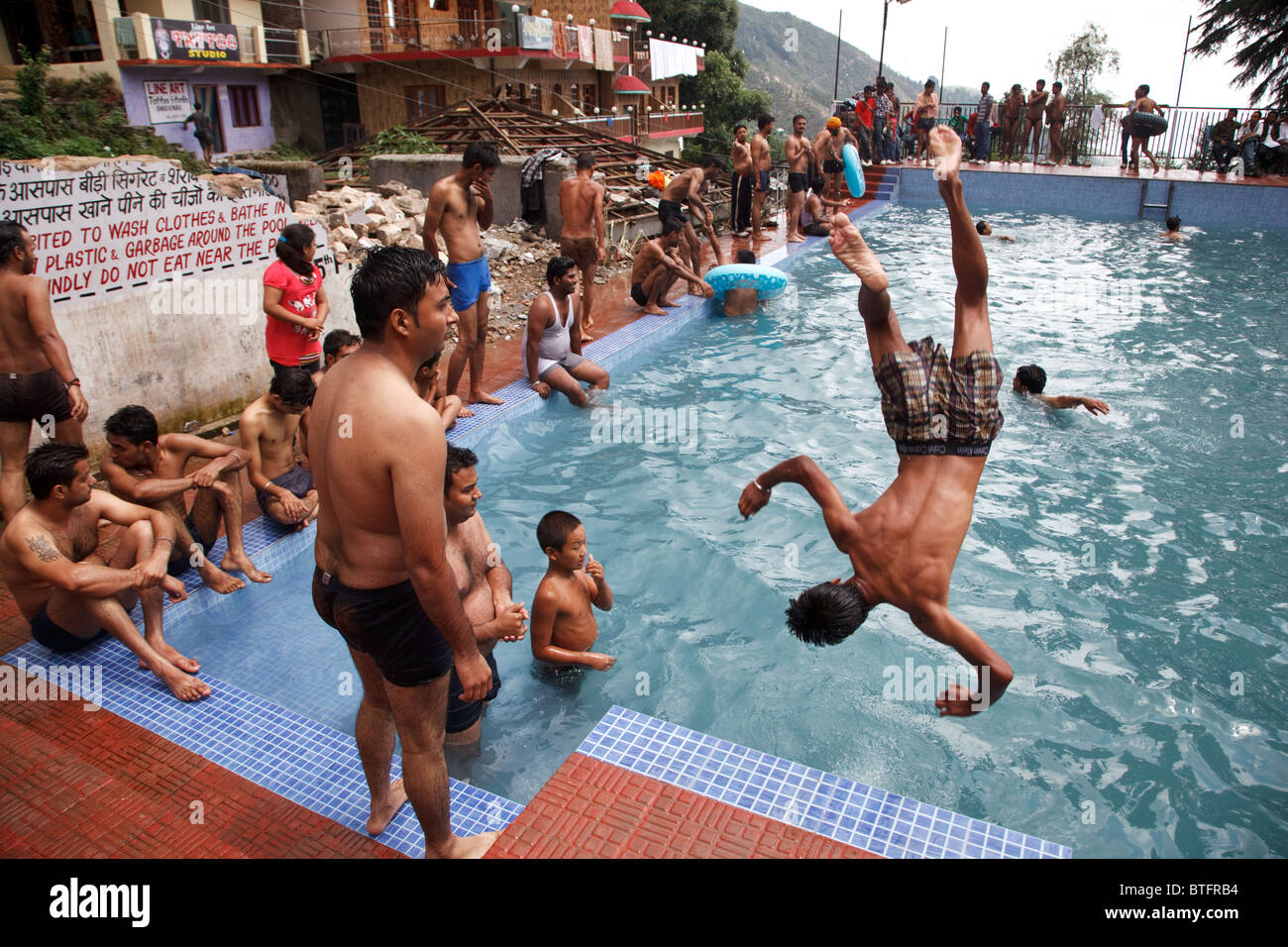 Un gruppo di giovani uomini salto in piscina pubblica in Bhagsu, Mcleod Ganj, India Foto Stock