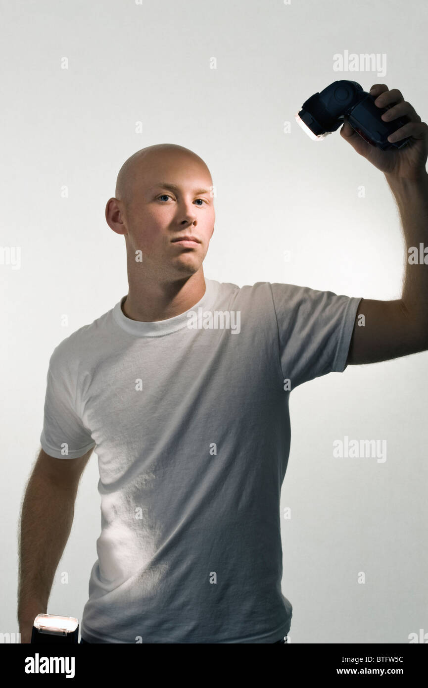 Uomo calvo (20-25) in un bianco tee shirt e sfondo bianco azienda videocamera wireless lampeggia. Foto Stock