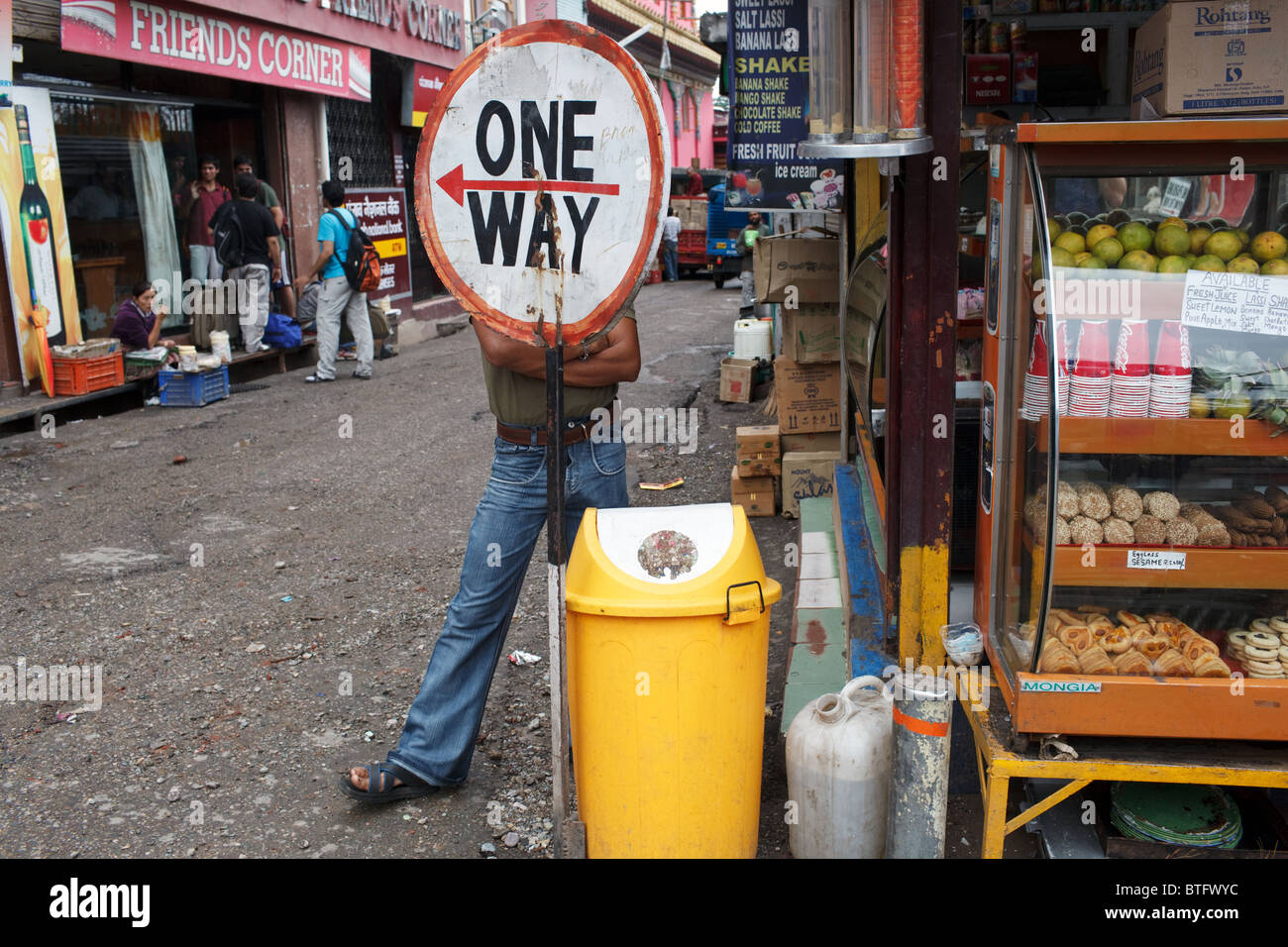 Un uomo dietro un cartello stradale in strada di McLeod Ganj, India Foto Stock