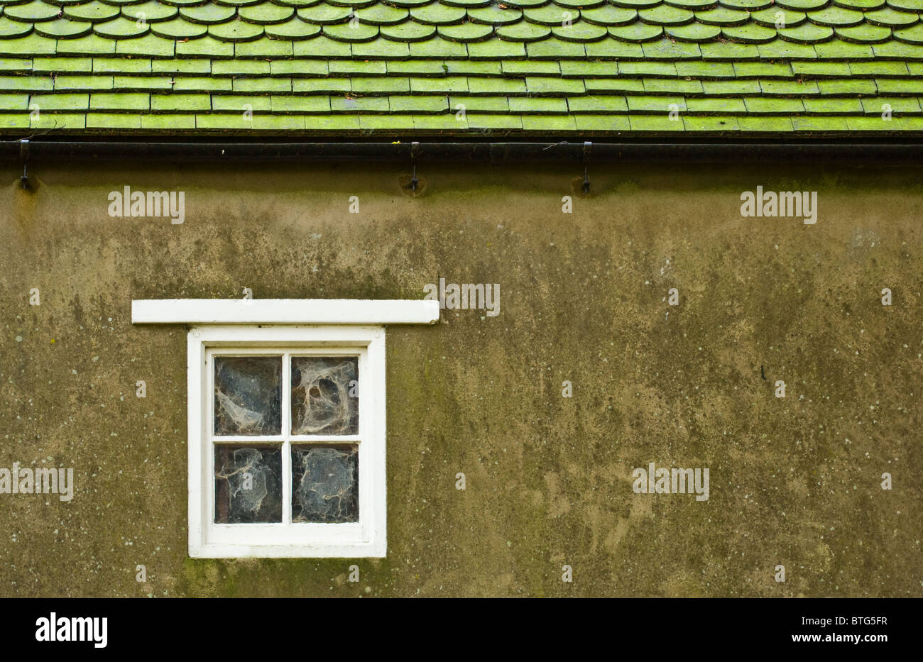 Fienile con un legno bianco sul telaio di una finestra, reso esterne di pareti e tetto di tegole. Foto Stock