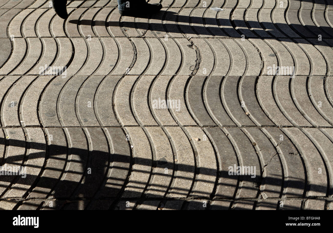Forti ombre proiettate dal Sole invernale sulla pavimentazione ondulata-le pietre a Las Ramblas, Barcelona Foto Stock