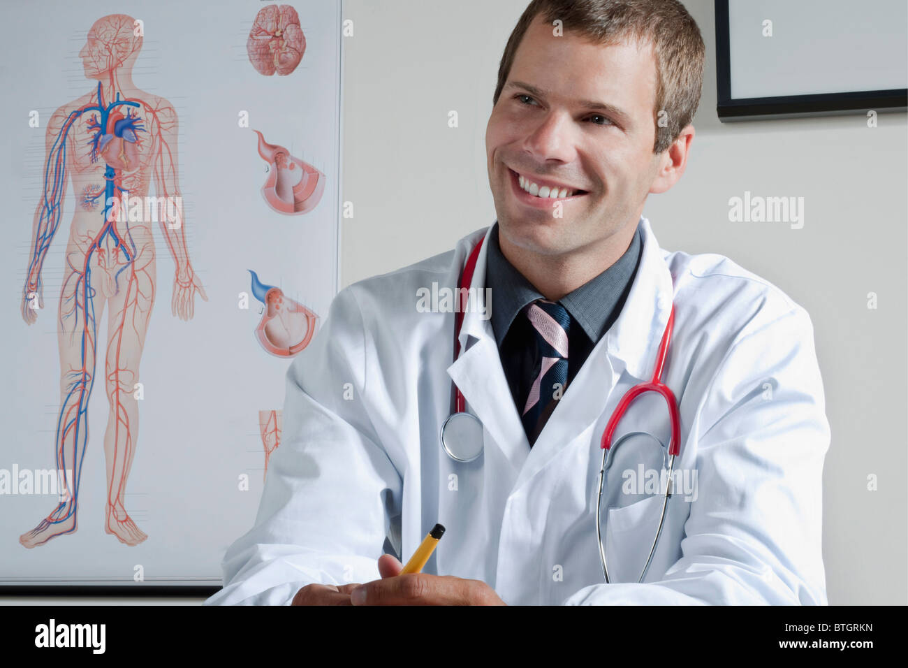 Medico nel suo ufficio con il sistema circolatorio grafico sulla parete Foto Stock