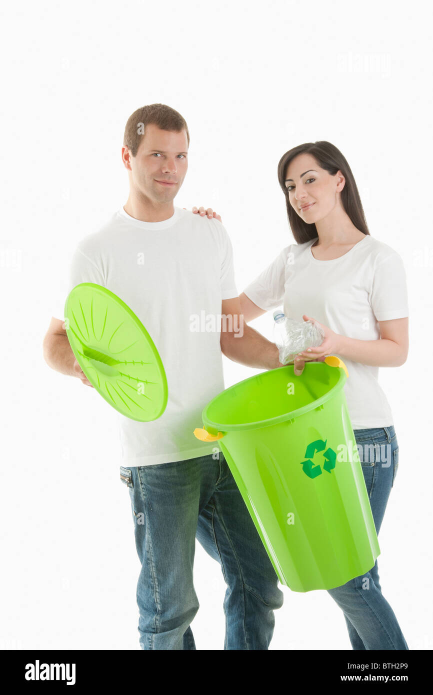 Paio di gettare la bottiglia di plastica nel contenitore di riciclaggio Foto Stock