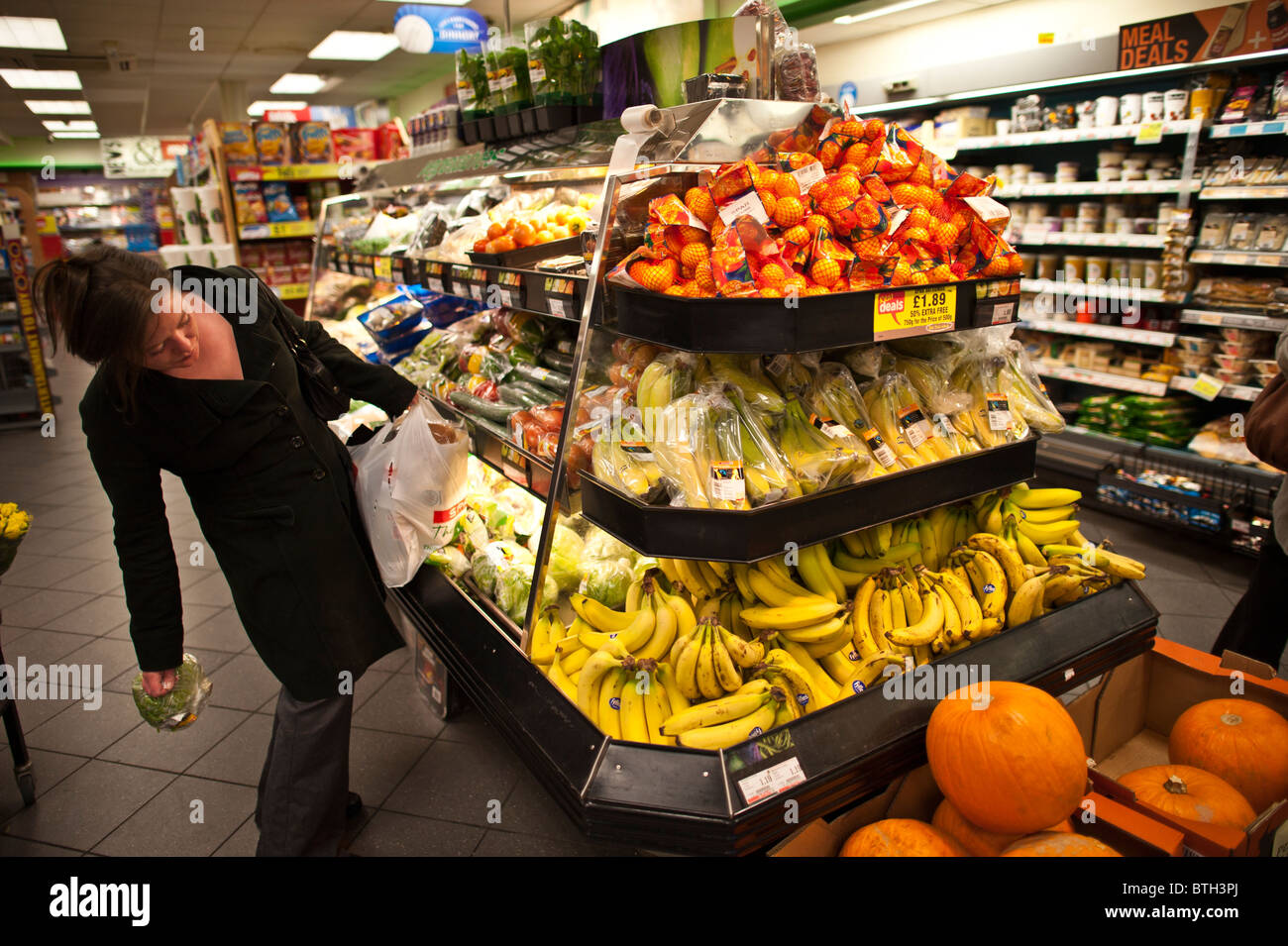 Una donna shopper guardando la frutta fresca e verdure di Spar supermercato UK Foto Stock