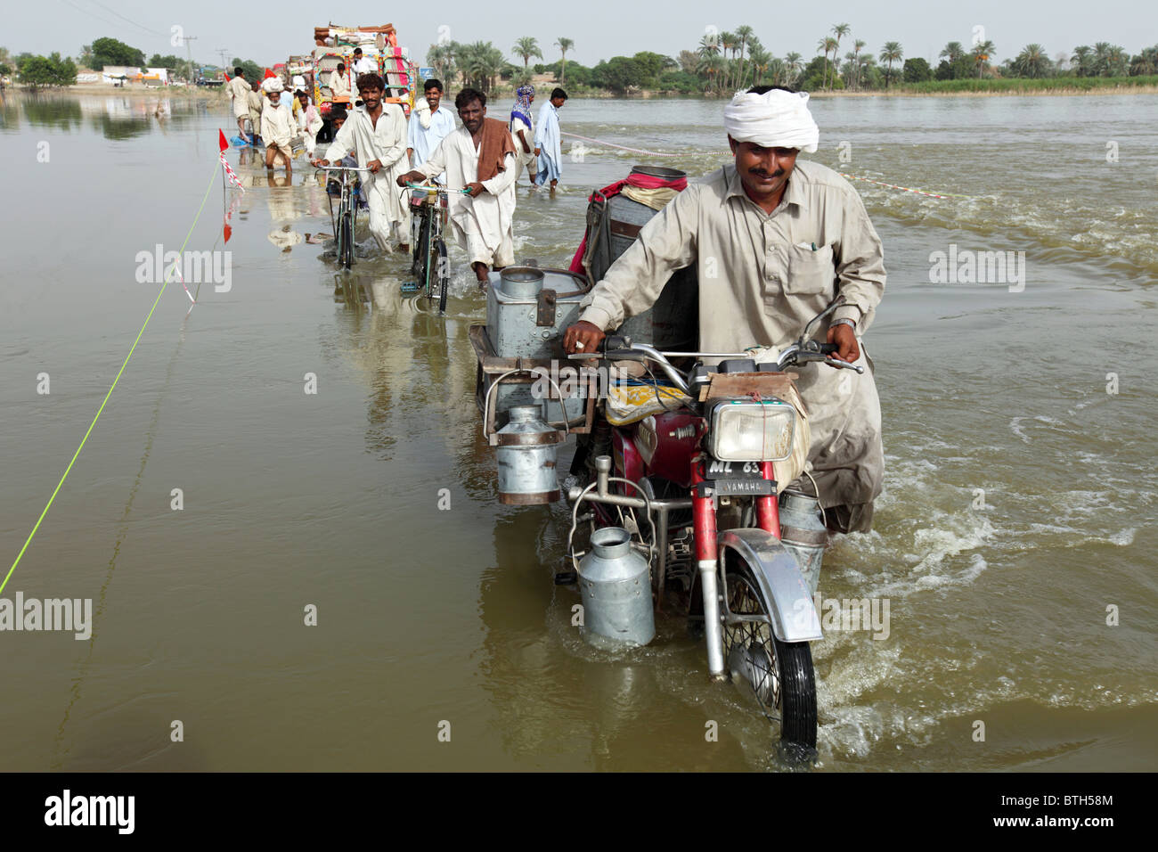 Persone che attraverso strade allagate, Muzaffargarh, Pakistan Foto Stock