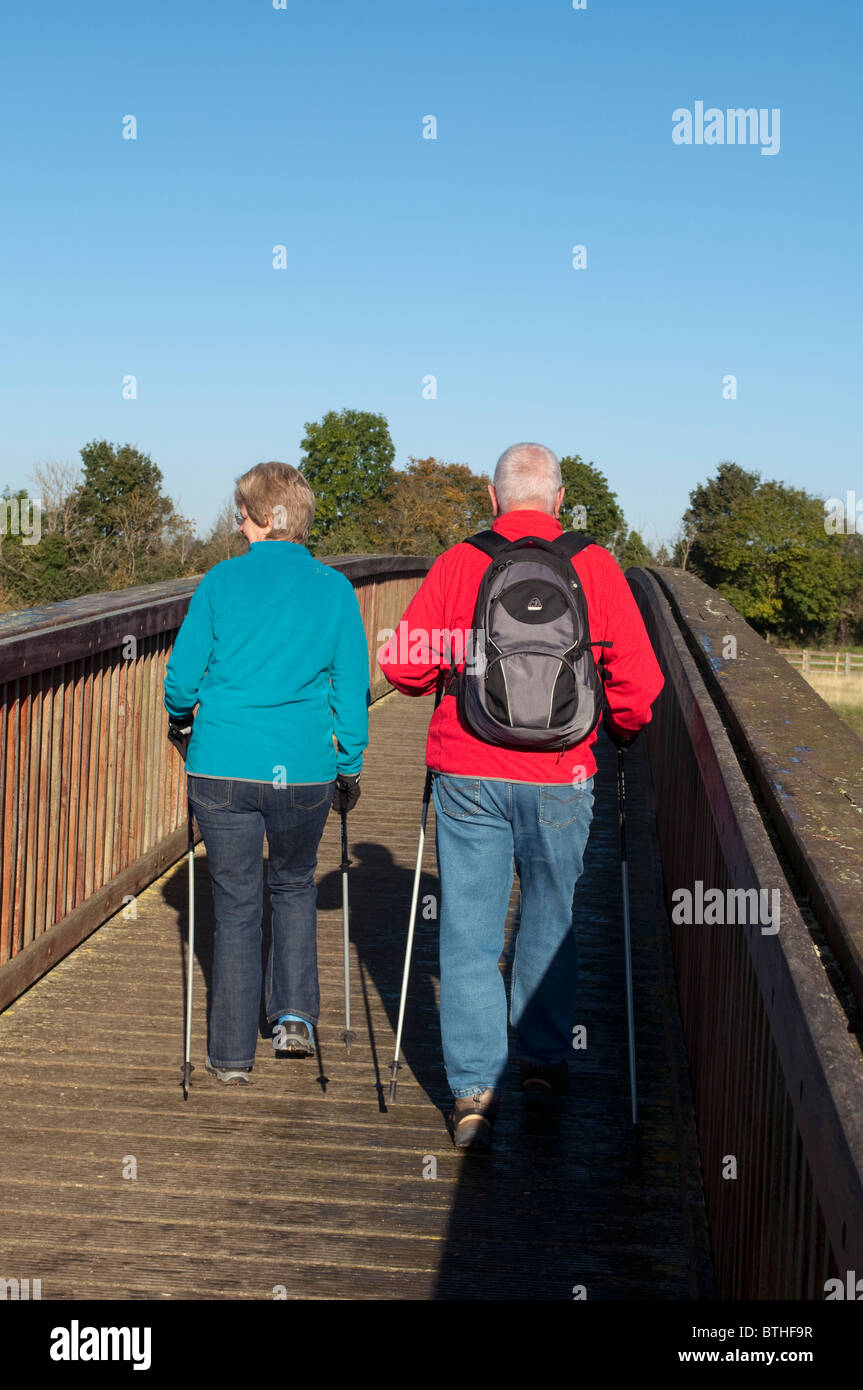 Due persone di mezza età camminatori con poli escursioni a piedi attraverso un ponte di legno sopra il Giubileo Rive. Foto Stock