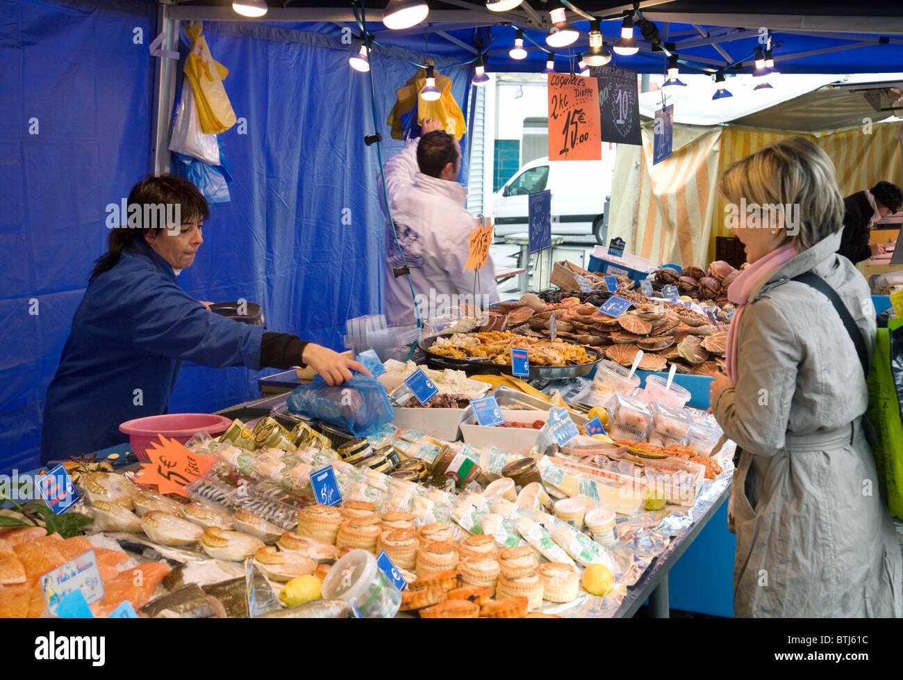 Una donna l'acquisto di pesce dal pescivendolo sul pesce fresco in stallo, Coulommiers street market vicino a Parigi, Ile de France Francia Foto Stock