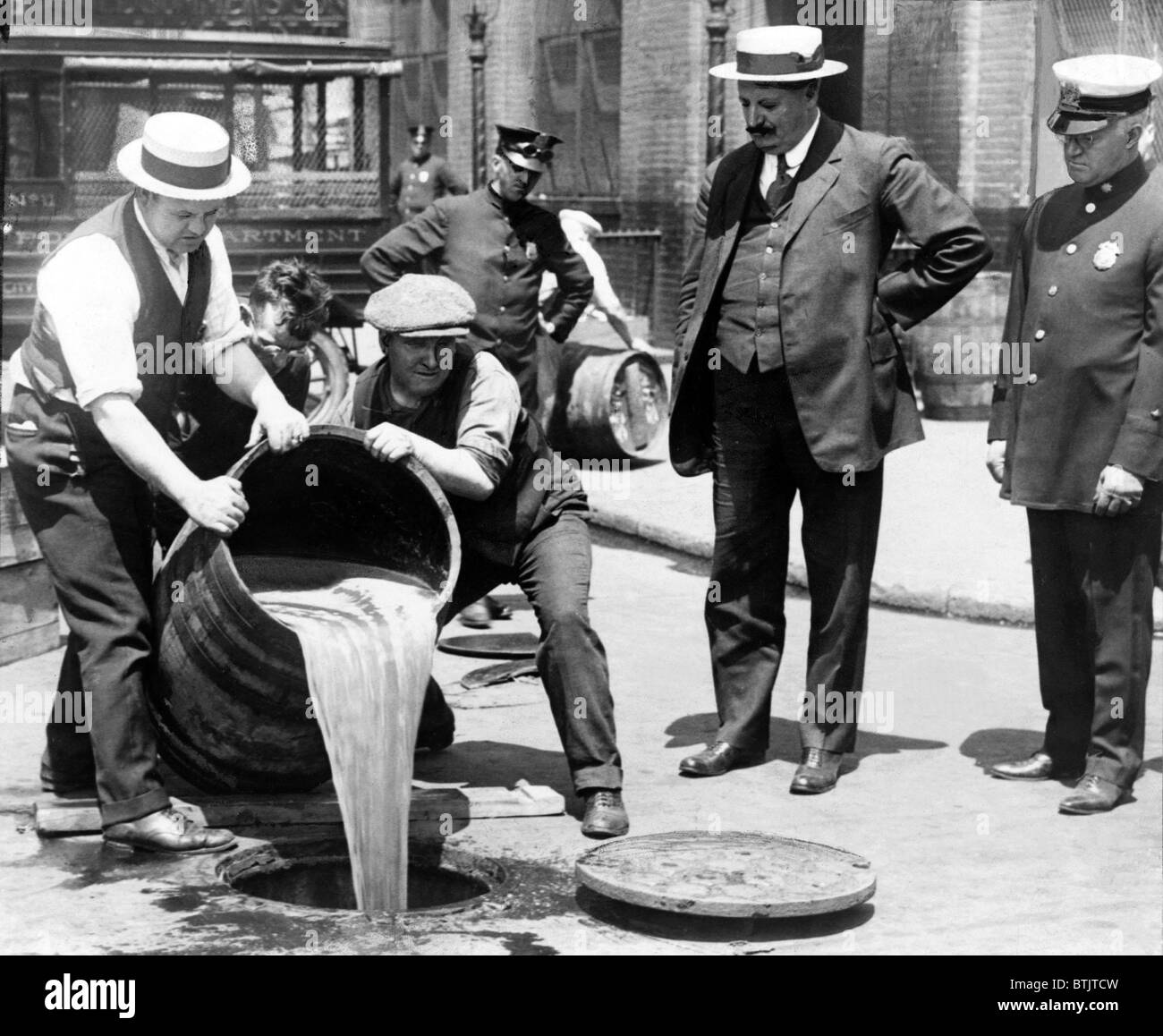 New York City vice commissario di polizia John A. Leach, destra, guardando gli agenti per il liquore giù un tombino in seguito a un raid durante il proibizionismo 1921. Foto Stock