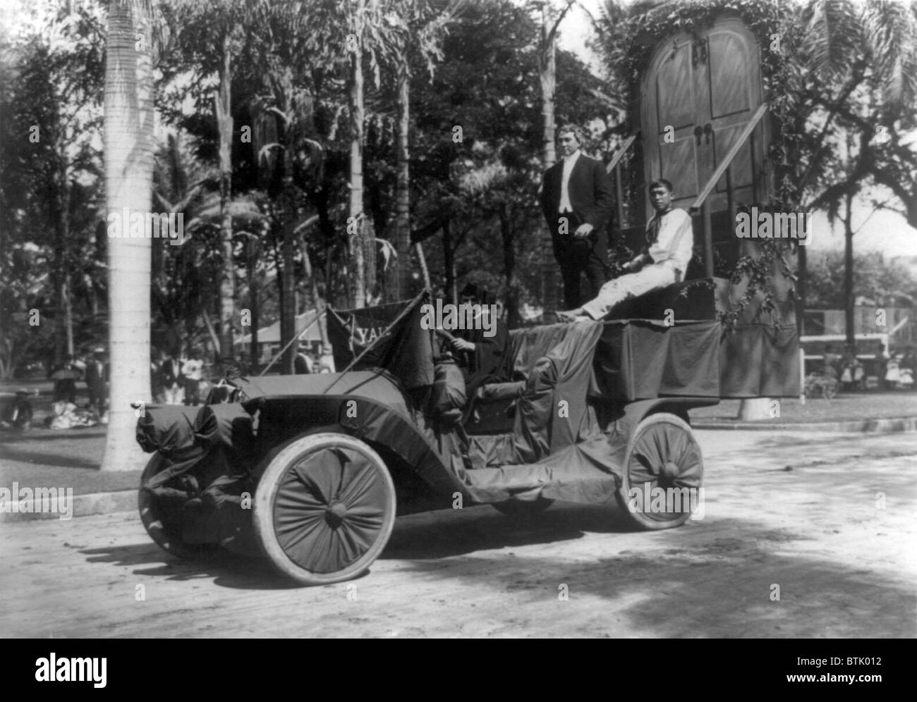 Tre uomini, uno vestito con cappuccio e vestaglia su auto con l'Università di Yale pennant utilizzato come galleggiare in una festa Hawaiiana, titolo: 'Ubediah cerca di conoscenze sulle fasi di vecchio Eli', fotografia, 1900-1915. Foto Stock