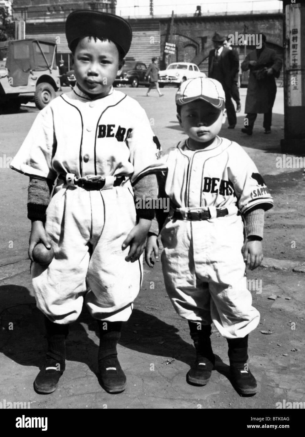 Bambini giapponese indossa baseball americano uniformi. ca 1950. La cortesia: Archivi CSU/Everett collezione. Foto Stock