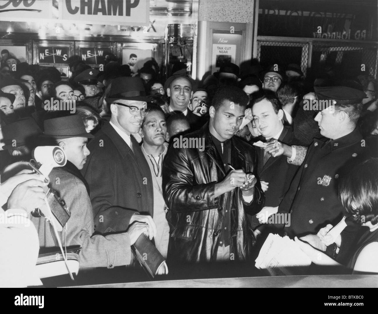 Muhammad Ali (Cassio argilla) sconfitto Sonny Liston per il pugilato Heavyweight Championship e ha annunciato la sua conversione alla nazione dell'Islam due giorni più tardi. Mostra fotografica di ali di firma autografi in New York City con Malcolm X alla sua destra, 1964. Foto Stock