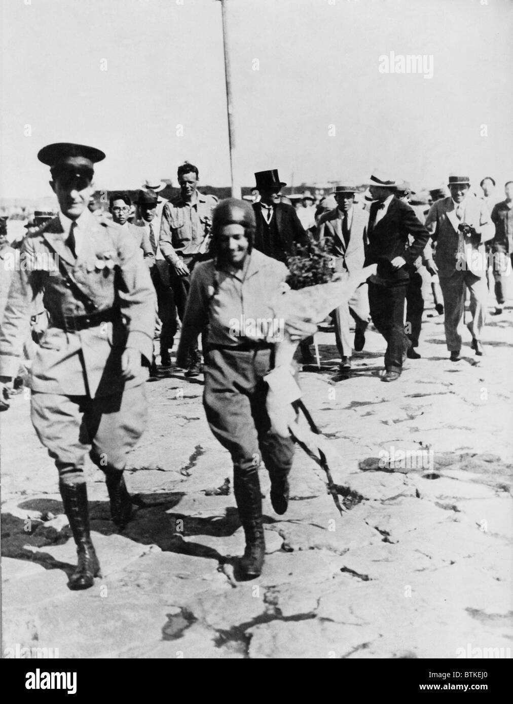 La sig.ra Anne Morrow Lindbergh scortato dal giapponese ufficiale, con il marito, Charles (in background) dopo il loro arrivo a Nemuro, Giappone. La loro 1931 volo su Canada e Alaska è stato il pioniere della futura aviazione commerciale rotte. Foto Stock