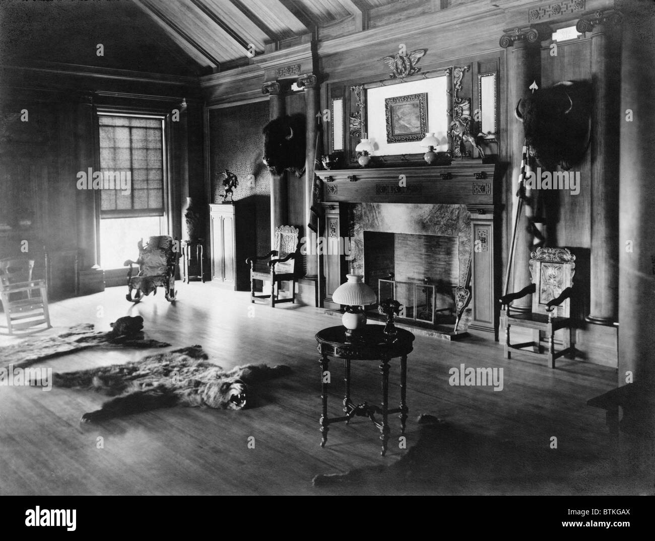 Sala dei trofei al Sagamore Hill, sede estiva del Presidente Theodore Roosevelt, con teste di bisonte e un bearskin rug davanti a un caminetto. Ca. 1905. Foto Stock