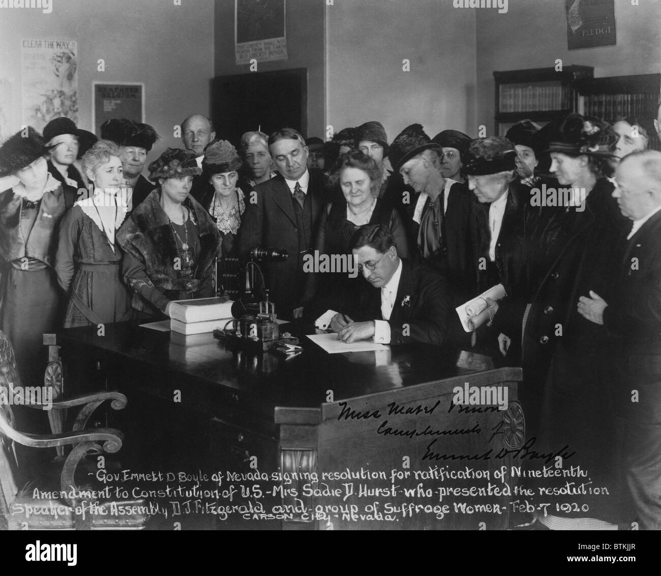 Governatore Emmett D. Boyle di Nevada firma una risoluzione per la ratifica del diciannovesimo emendamento alla costituzione degli Stati Uniti come un gruppo di suffragists guarda. Foto Stock