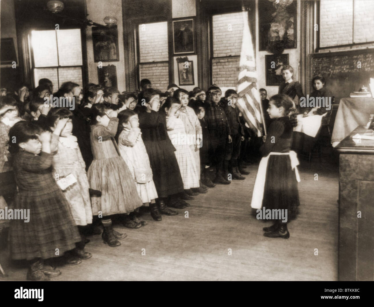 I bambini immigrati salutando la bandiera in Mott Street Scuola Industriale, N.Y.C. 1889 foto di Jacob Riis. Foto Stock