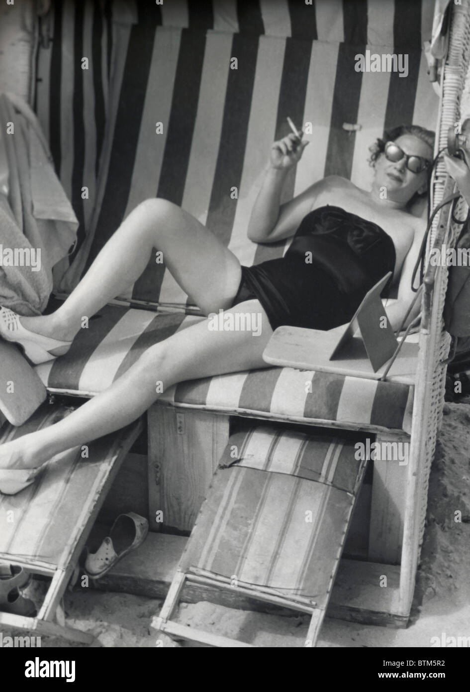 Foto storiche (1910) di una donna seduta su una sedia di spiaggia Foto Stock