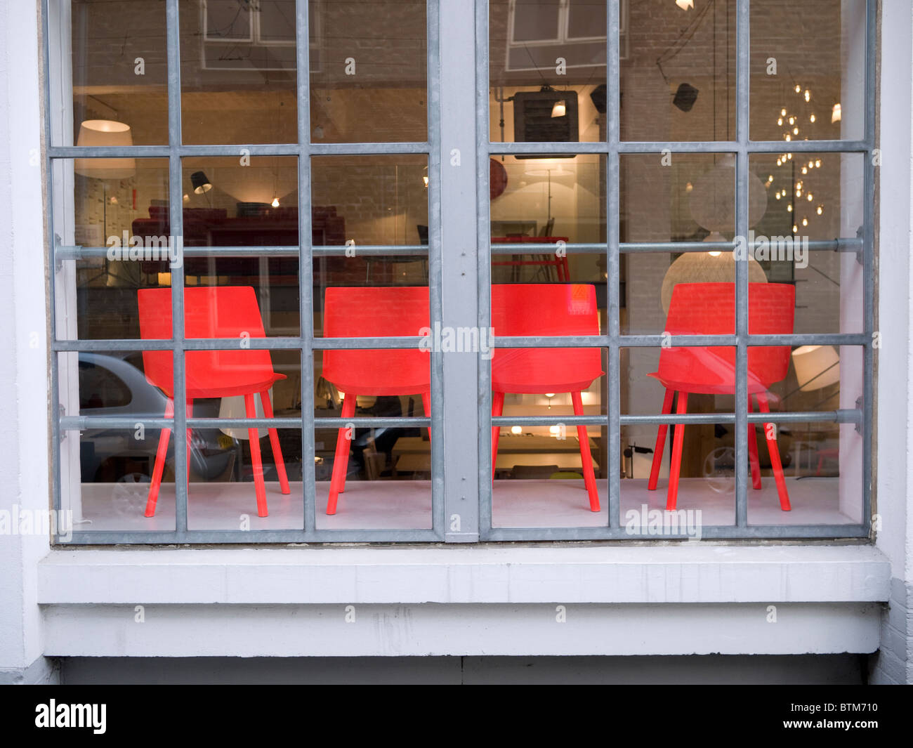 Red designer sedie in un negozio di mobili di Londra la finestra Foto Stock