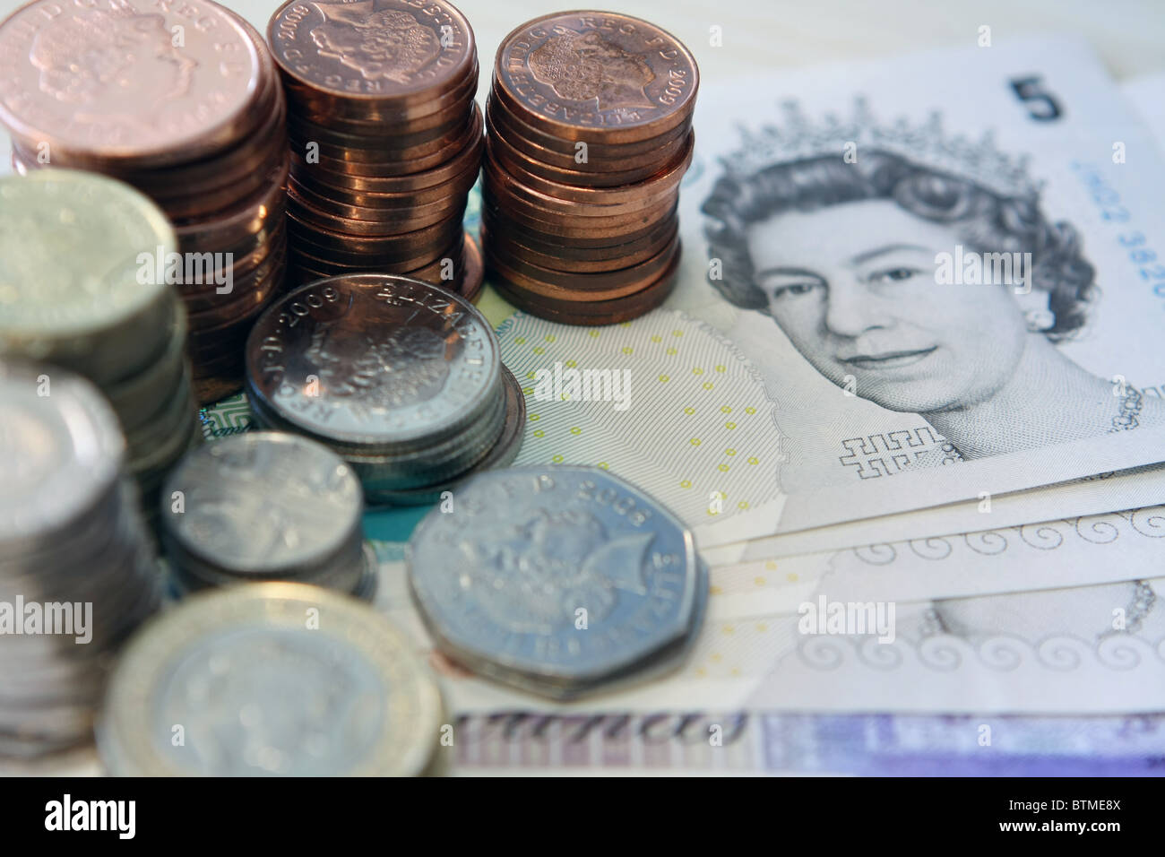 Pile di sterling monete sulle note di sterling Foto Stock