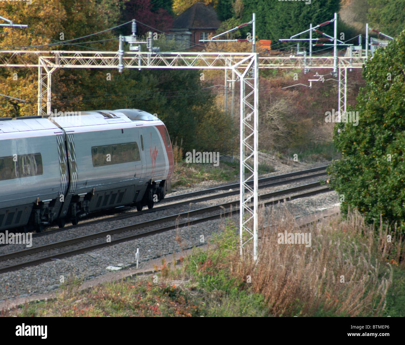 Vergine di treno che viaggia sotto la ferrovia Gantry Foto Stock