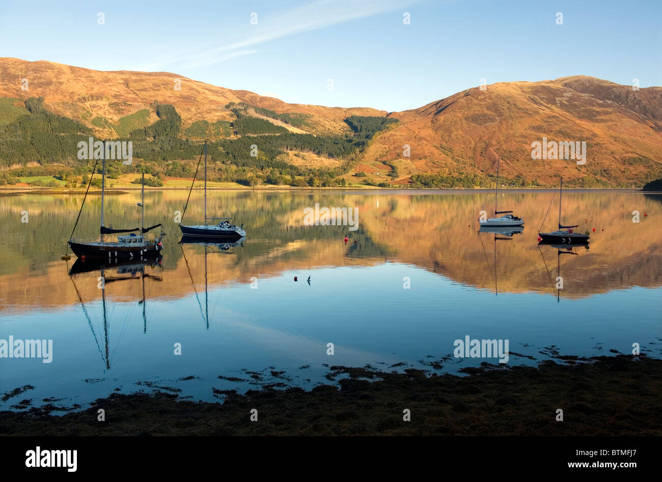 Loch Leven a sud di Ballachulish vicino a Glen Coe, Argyll, Scozia. Riflessioni perfetto nelle prime ore del mattino nitido luce. Foto Stock