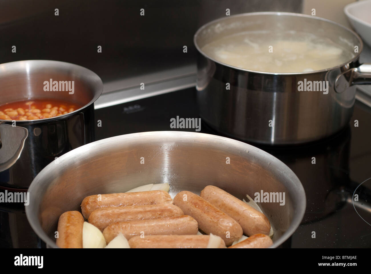 Salsicce, fagioli e schiacciare la cottura sul piano di cottura Foto Stock