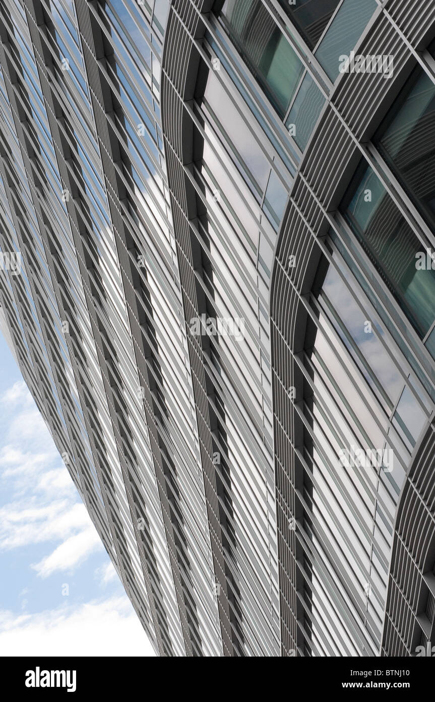Vista della curva esterna edificio per uffici a guardare in alto verso il blu e il cielo nuvoloso Foto Stock
